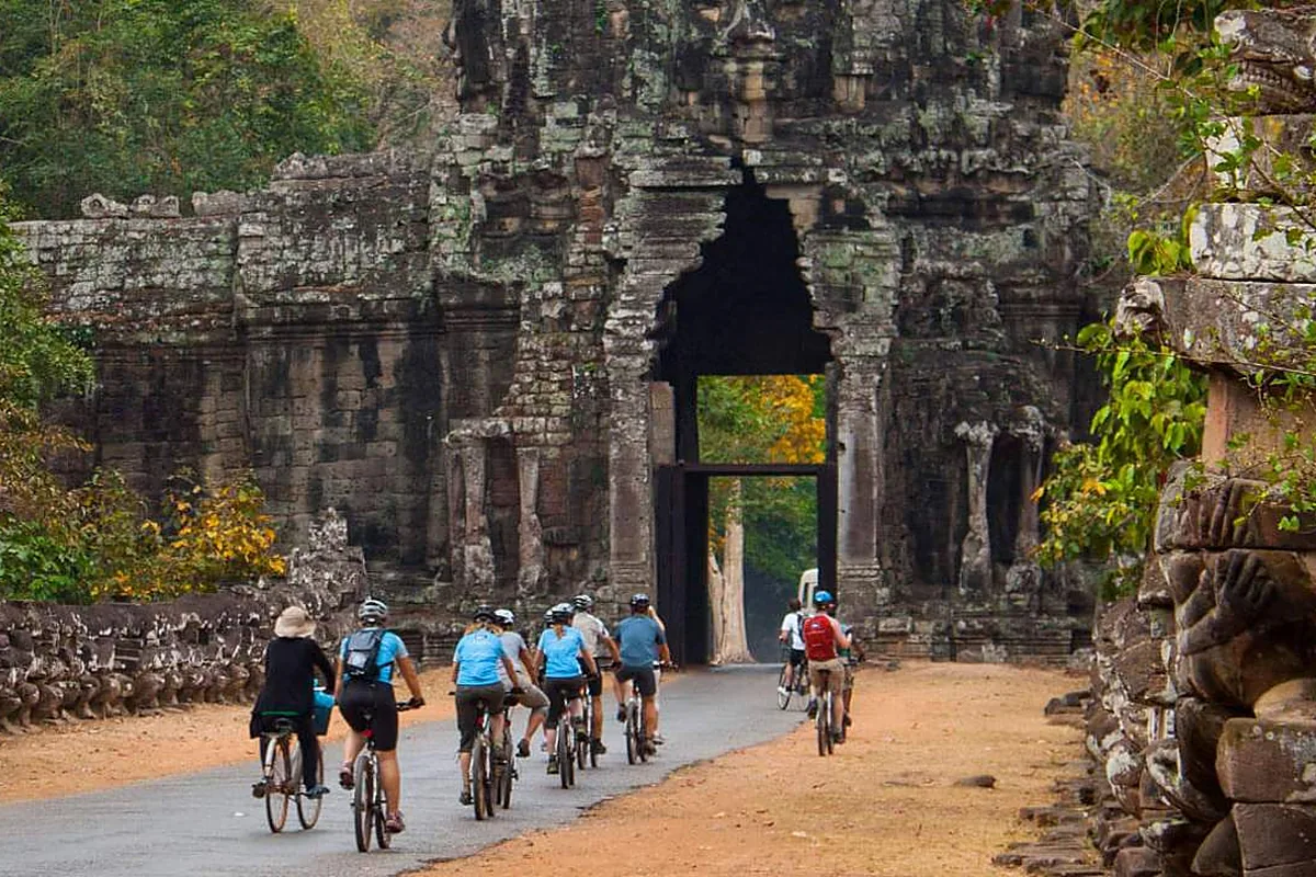 Students cycling through an Angkor temple gate in Siem Reap, Cambodia