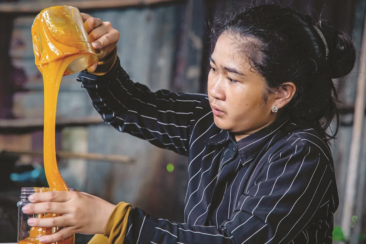 Local artisan pouring fresh honey during a community visit